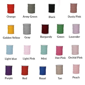 Op de afbeelding: Een verzameling van 15 spoelen met gekleurd garen in verschillende tinten oranje, geel, groen, blauw, roze, rood, paars, bruin en zwart. Het garen is gerangschikt in een raster.