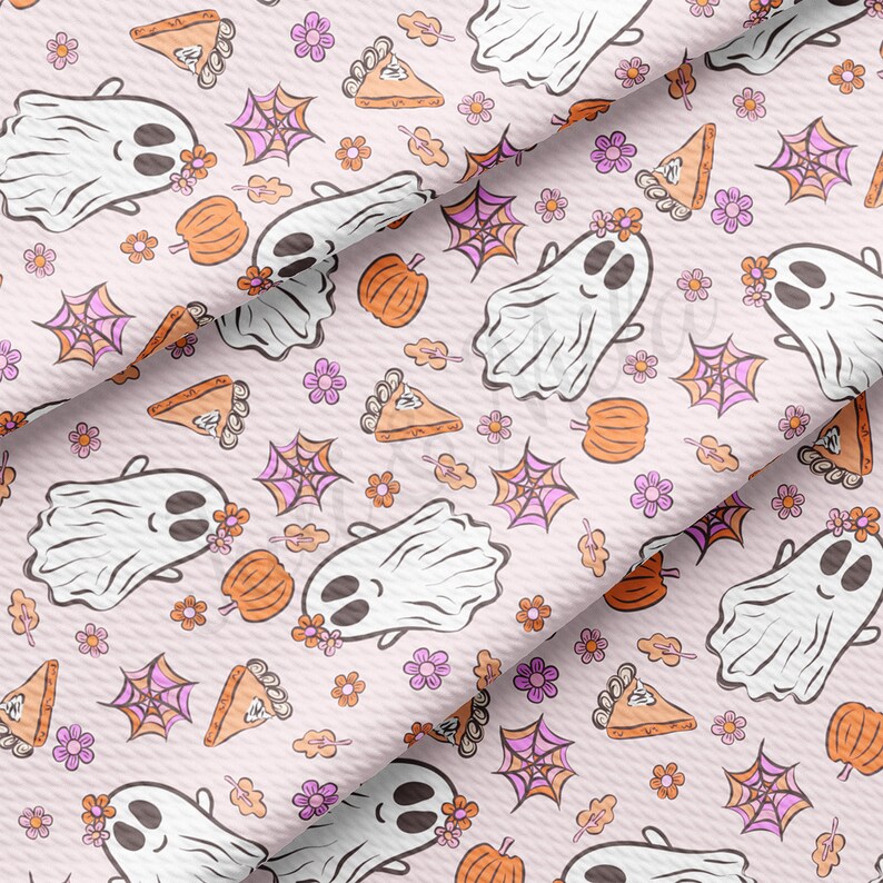 May include: A pale pink fabric featuring a repeating pattern of smiling ghosts, pumpkins, spiderwebs, flowers, and pie slices. The ghosts wear floral crowns. Ideal for Halloween or autumn-themed craft projects.
