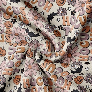 May include: A beige fabric with a repeating pattern of the words "Hocus Pocus" in a retro font, along with stylised pumpkins and flowers. The fabric is folded and textured.