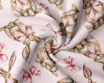 May include: A pink fabric with a repeating pattern of brown bunnies wearing pink bows. The bunnies are in various poses and the background is a light pink with white dots.