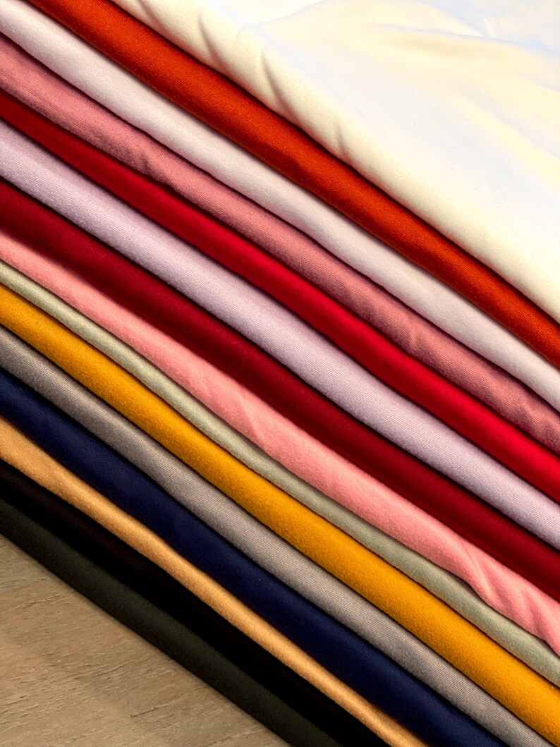 Pu&ograve; includere: Un assortimento di campioni di tessuto in vari colori, tra cui bianco, arancione, rosa, rosso, viola, giallo, blu, grigio, beige e nero.