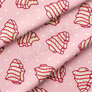 May include: Pink fabric with a repeating pattern of white and red striped Christmas trees with green accents. The fabric has a subtle texture and white polka dots.