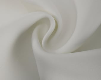Puede incluir: Tela blanca con una textura suave y sedosa. La tela está doblada y drapeada, creando pliegues y curvas suaves.