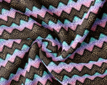 May include: A brown fabric with a chevron pattern in shades of pink, blue, and purple. The fabric has a glittery texture.