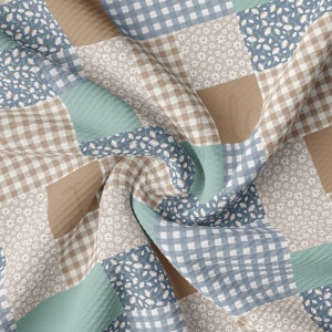 Puede incluir: Una tela de patchwork con una variedad de patrones, incluyendo cuadros, flores y colores sólidos. La tela está en tonos de marrón, azul y verde.