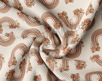 May include: A beige fabric with a repeating pattern of rainbows with brown, pink, and green stripes. Each rainbow has a cluster of brown mushrooms and leaves at the top.