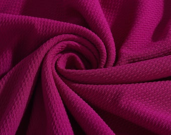 May include: Close-up of a deep pink fabric with a textured, woven pattern. The fabric is folded and draped, creating a soft, flowing look.