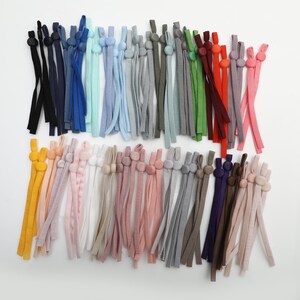 May include: A collection of colorful elastic straps with adjustable plastic toggles. The straps are made of a variety of materials, including cotton, nylon, and polyester. The toggles are available in a variety of colors, including black, white, red, blue, green, and yellow.