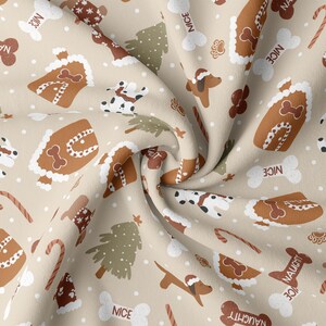 Puede incluir: Una tela beige con un patrón repetido de casas de jengibre, bastones de caramelo, árboles de Navidad, perros con gorros de Papá Noel y huesos en forma de adornos con las palabras "Nice" y "Naughty".