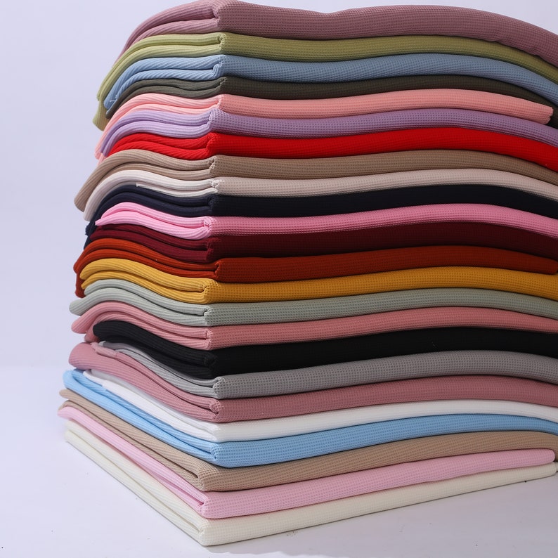 May include: A stack of 20 different colored waffle knit fabric swatches. The colors include beige, white, pink, light blue, gray, black, brown, red, and yellow.