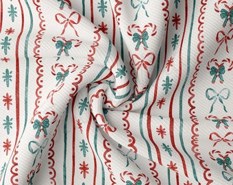 Peut inclure: Tissu blanc avec un motif répété de rayures rouges et vertes, de cannes en sucre et de nœuds. Le tissu est plié et texturé.