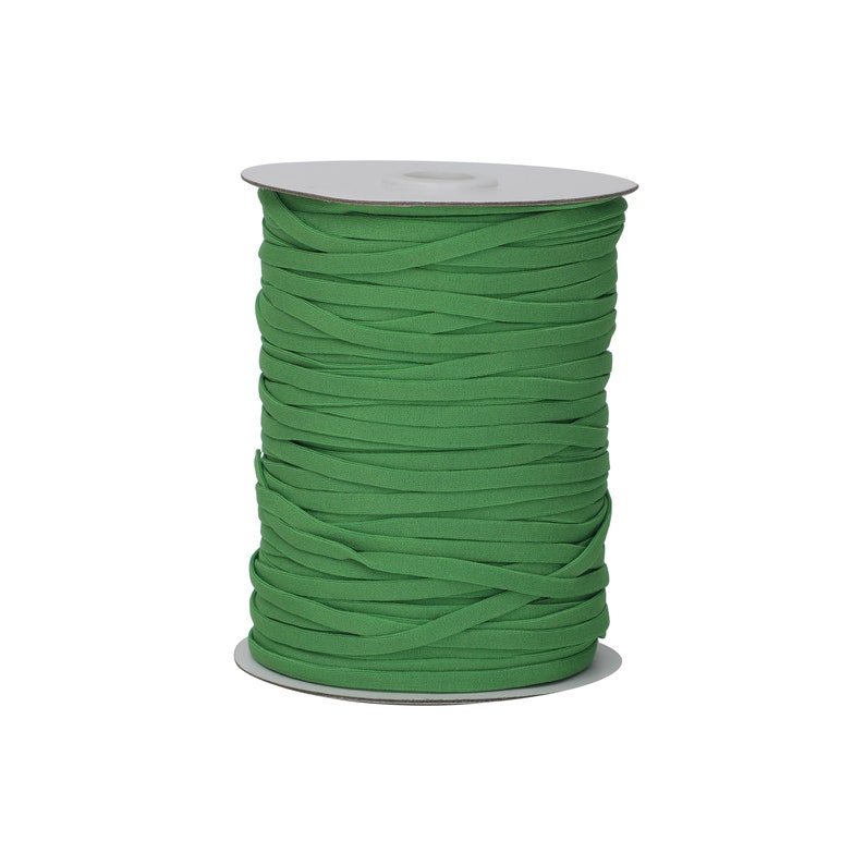 Op de afbeelding: Een spoel met groene elastische koord, strak gewikkeld op een witte kartonnen spoel.