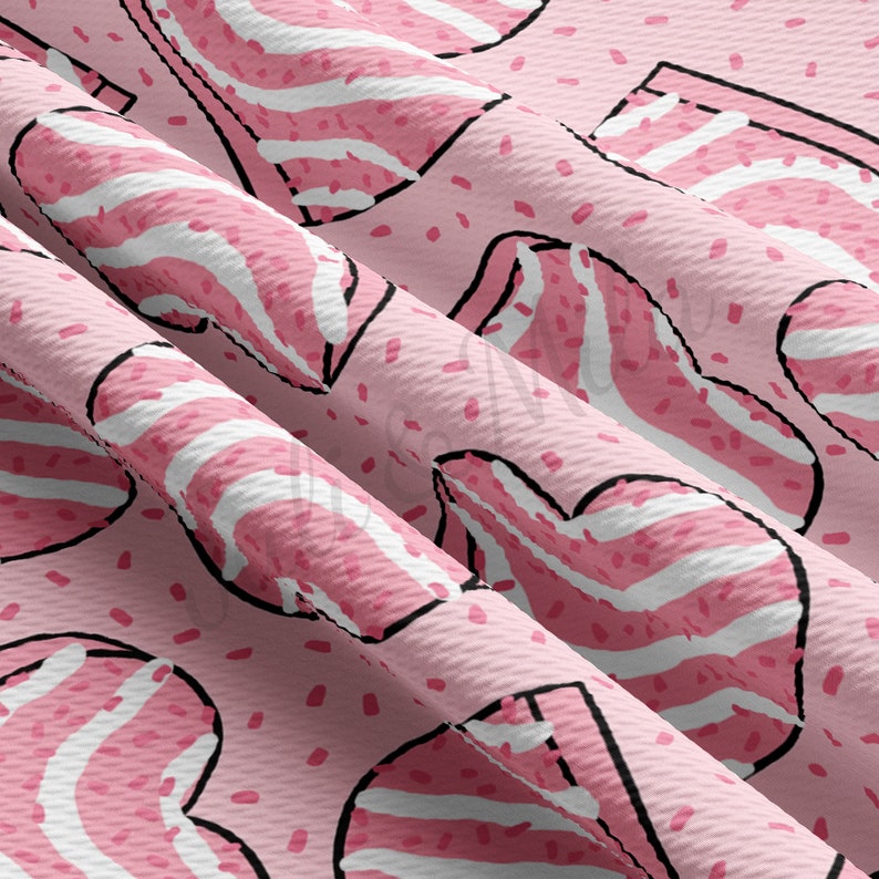 May include: A close-up of a pink fabric with a repeating pattern of bacon slices. The bacon is pink with white stripes and outlined in black. Small pink speckles are scattered across the light pink background.