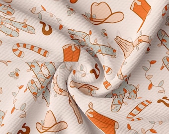 Peut inclure: Un tissu blanc avec un motif répété de chapeaux de cowboy, de bottes, de cannes en sucre et de cactus avec des lumières de Noël. Le tissu a une texture en nid d'abeille.