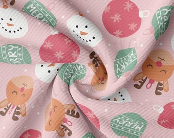 Peut inclure: Tissu rose avec un motif répété d'ornements de Noël, de bonhommes de neige, de rennes et du mot "Merry".