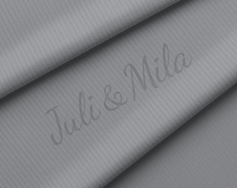 Puede incluir: Primer plano de una tela gris acanalada con el texto "Juli & Mila" impreso en ella.