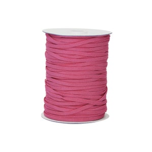 Op de afbeelding: Een spoel met roze elastisch koord, strak gewikkeld op een witte kartonnen spoel.