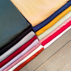 Pu&ograve; includere: Un mucchio di tessuto piegato in vari colori, tra cui verde acqua, nero, grigio, rosso, rosa, bianco, arancione, verde, giallo e blu.