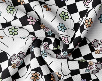 Könnte beinhalten: Schwarz-weiß kariertes Stoff mit einer weißen Umrandung einer Blume mit bunten Blütenblättern. Der Stoff ist gefaltet und die Blumen wiederholen sich im gesamten Muster.