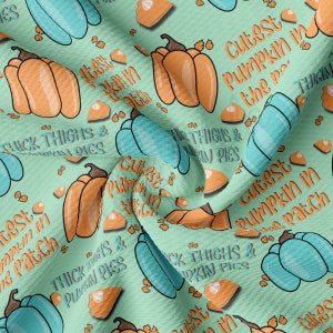 May include: A light green fabric with a repeating pattern of orange and teal pumpkins, pumpkin pie slices, and text that reads "Cutest Pumpkin in the Patch" and "Thick Thighs & Pumpkin Pies".