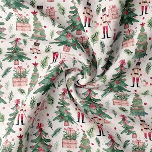 May include: White fabric with a repeating pattern of watercolor Christmas trees, wrapped gifts, nutcrackers, and sprigs of greenery. The trees are decorated with red bows and ornaments. The gifts are wrapped in pink paper.