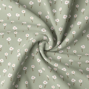 May include: A green fabric with a white floral pattern. The fabric is folded and has a soft, textured surface.