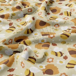 May include: A beige fabric with a repeating pattern of brown and yellow bees, sunflowers, and white flowers. The fabric has a textured waffle weave.