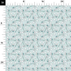 以下が含まれることがあります： 白い歯、歯ブラシ、歯磨き粉のチューブが繰り返し描かれた薄い青色の生地。パターンは白いドットが散りばめられた白い背景に描かれている。