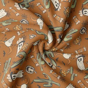 May include: A brown fabric with a repeating pattern of Halloween-themed illustrations. The pattern includes ghosts, cacti, bats, candy, and skulls. The fabric is folded and textured.