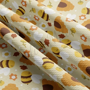May include: A beige fabric with a repeating pattern of yellow and brown bees, brown sunflowers, and white daisies.