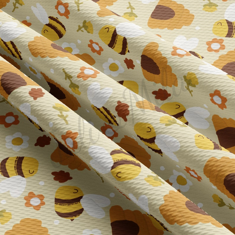 May include: A beige fabric with a repeating pattern of yellow and brown bees, brown sunflowers, and white daisies.