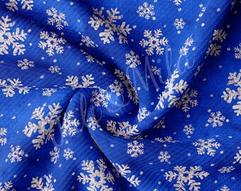 以下が含まれることがあります： 白い雪の結晶模様の青い布。布はしわくちゃで、表面に凹凸がある。