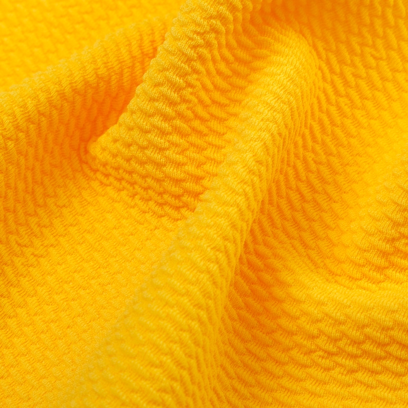 May include: Close-up of a bright yellow textured fabric with a rippled pattern.
