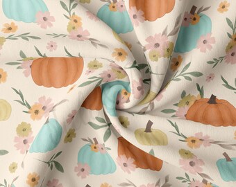 May include: A cream-colored fabric with a repeating pattern of orange and teal pumpkins, green leaves, and pink and yellow flowers.
