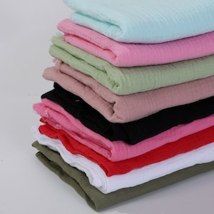 Puede incluir: Una pila de 10 cuadrados de tela en varios colores, incluyendo azul claro, rosa, verde, beige, negro, rojo, blanco y verde oliva. La tela tiene una textura de tipo waffle.