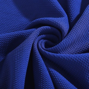 May include: Close-up of a textured blue fabric. The fabric has a waffle-like pattern and is folded in a spiral shape.