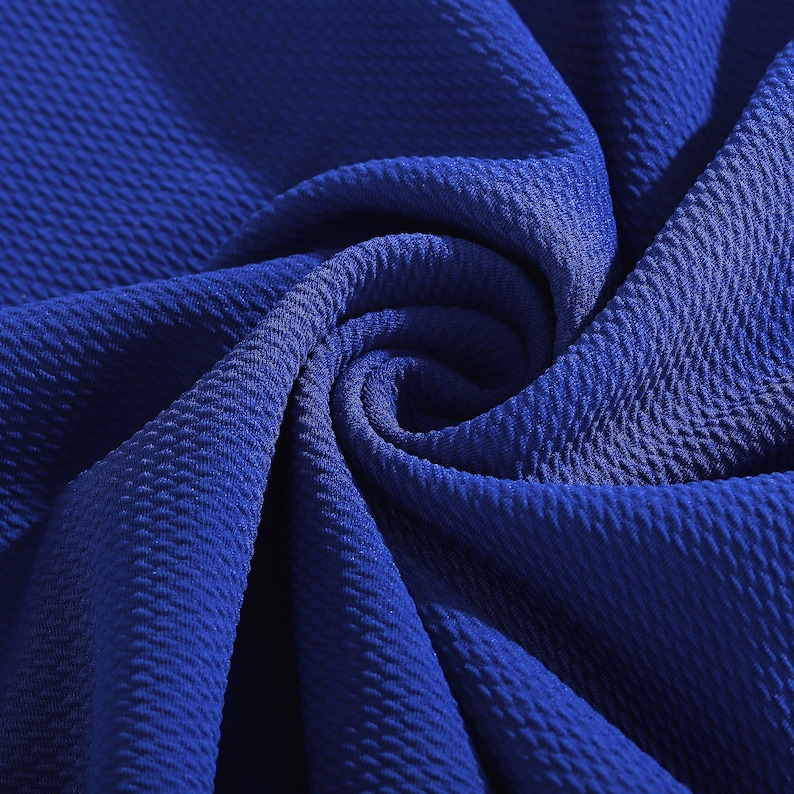 May include: Close-up of a textured blue fabric. The fabric has a waffle-like pattern and is folded in a spiral shape.
