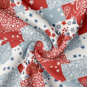 May include: A close-up of a fabric with a patchwork design. The pattern features red, white, and blue squares with floral, paisley, and star motifs. The fabric has a textured appearance, with a slight wave effect.