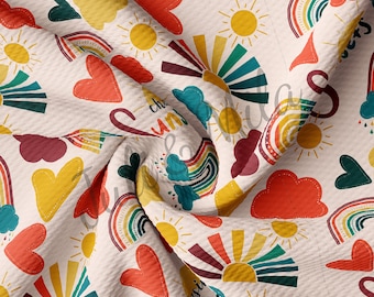 May include: A white fabric with a repeating pattern of rainbows, suns, clouds, and hearts. The colors are red, orange, yellow, green, blue, and purple. The text "chase the sun" and "love the night" is included in the pattern.