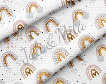 May include: White fabric with a repeating pattern of rainbows, hearts, and raindrops. The rainbows feature shades of brown, pink, and blue with black polka dots. The design is suitable for various craft projects.