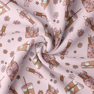 May include: A pink fabric with a repeating pattern of brown pencils, flowers, and cups with bows. The fabric is folded and textured.