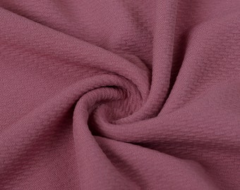 May include: Close-up of a soft, textured fabric in a dusty rose color. The fabric is wrinkled and folded, showing its texture and drape.