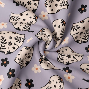 May include: A purple fabric with a repeating pattern of white ghosts with black floral designs. The ghosts are surrounded by small white and black flowers.