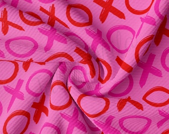 May include: Pink fabric with a repeating pattern of red and pink circles and Xs. The fabric is folded and textured.