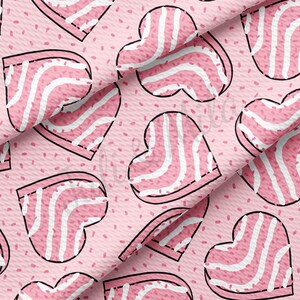 May include: A repeating pattern of pink heart shapes with white stripes and black outlines on a light pink background. The hearts are scattered across the fabric, with small pink sprinkles adding detail. The fabric has a textured appearance.