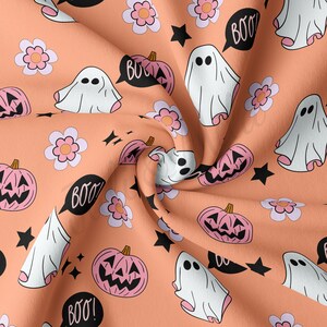 May include: A peach-colored fabric with a repeating Halloween-themed pattern. The design includes white ghosts, pink jack-o'-lanterns, black stars, and pink and white flowers. Speech bubbles say "BOO!"