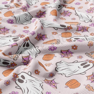 May include: A light pink fabric featuring a repeating pattern of white ghosts with flower crowns, orange pumpkins, purple spiderwebs, and flowers. The fabric has a textured appearance, with a subtle woven design.