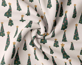Könnte beinhalten: Weißer Stoff mit einem sich wiederholenden Muster aus grünen Weihnachtsbäumen mit rosa und weißen Blüten und goldenen Sternen oben. Der Stoff ist gefaltet und verdreht.