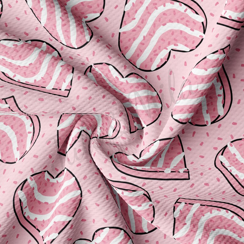 May include: Pink fabric with a repeating pattern of heart-shaped designs. Each heart has a black outline and is filled with pink and white stripes. Small pink speckles are scattered across the background.