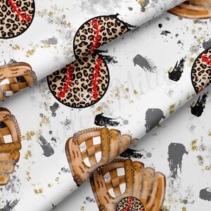 Op de afbeelding: Witte stof met een herhalend patroon van bruine honkbalhandschoenen en honkballen met luipaardprint. De achtergrond is wit met zwarte en grijze verfspatten.